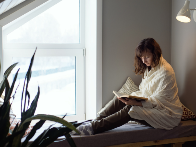 woman reading a book in a cozy window seat