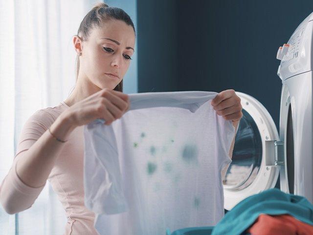 woman holding up a shirt with a stain