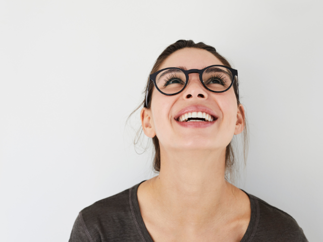 woman wearing glasses and looking up while smiling