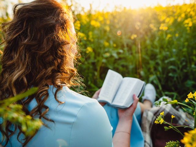woman reading in a field of flowers