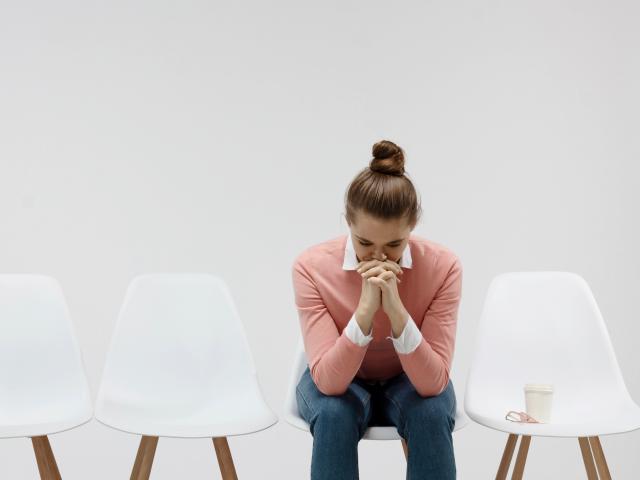 woman in pink sweater waiting in white room with white chairs
