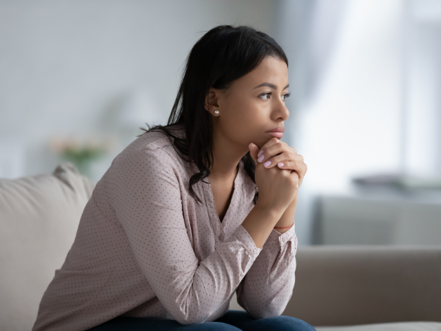 worried woman sitting alone on a couch