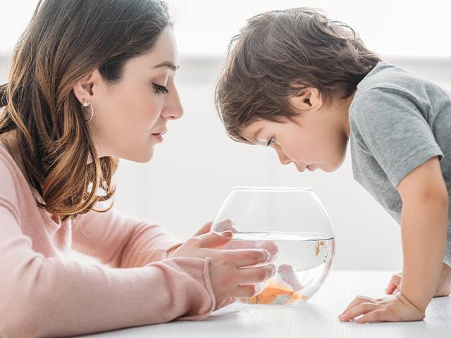 mother and son looking in a fishbowl at a goldfish