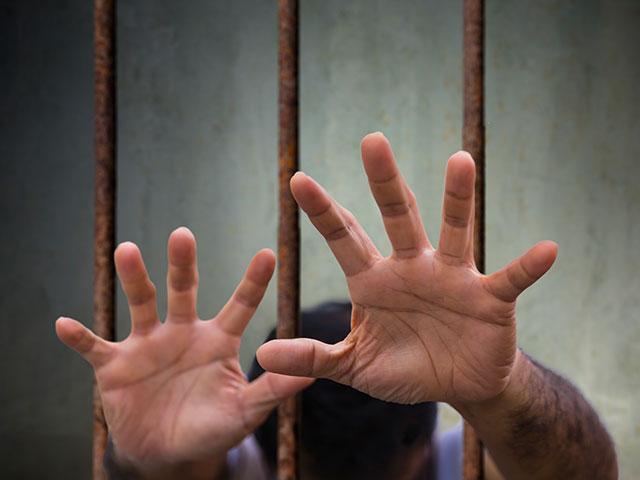 hands reaching out from prison bars