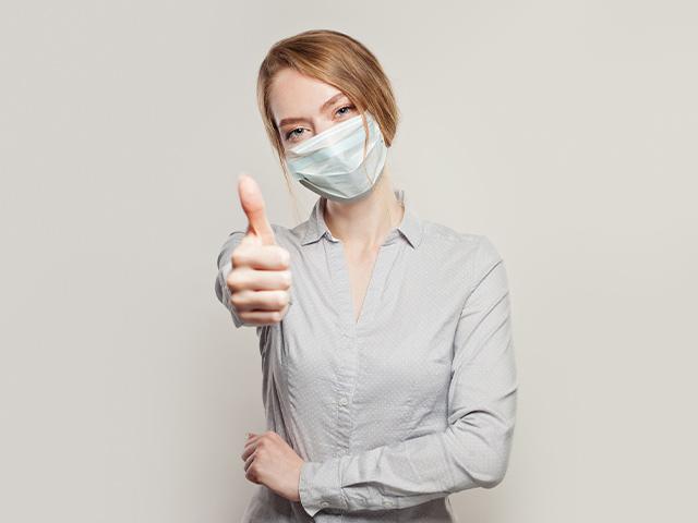 woman wearing a face mask with thumbs up gesture