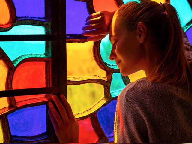 young woman leaning her head on pretty stained glass window