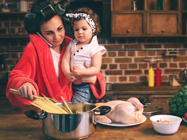 stressed mom with a baby on her hip in the kitchen