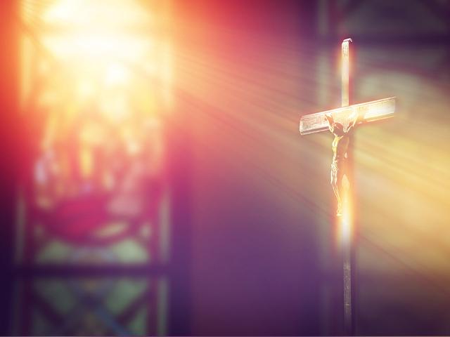 sun ray shining through church window to Jesus on the cross