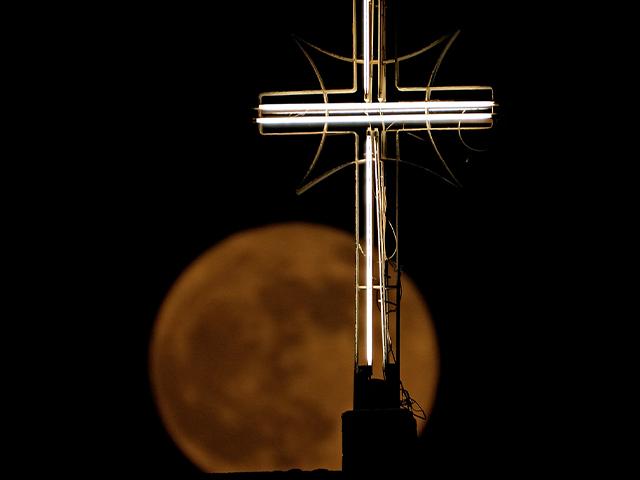 A supermoon rises over the cross of St. Joseph Church in Baghdad, Iraq, June 14, 2022. (AP/Photo/Hadi Mizban)