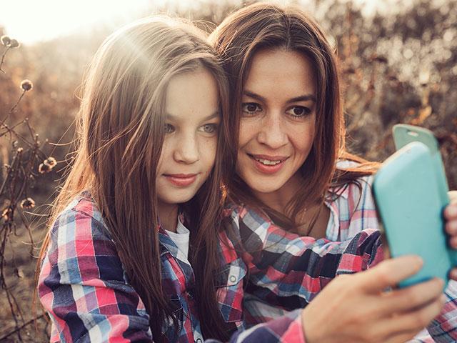 Tween girl with mom on cell phone