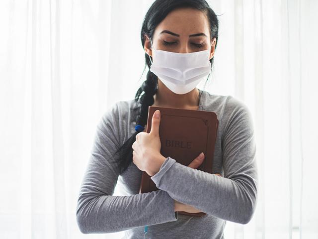 woman hugging her Bible and wearing a face mask during covid19 pandemic