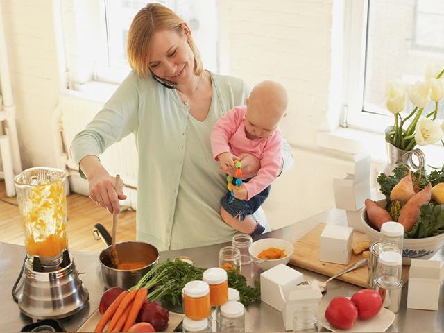 woman talking on her phone with a baby on her hip and cooking on the stove