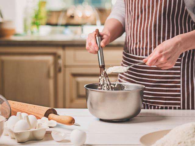 woman putting ingredients into a mixing bowl