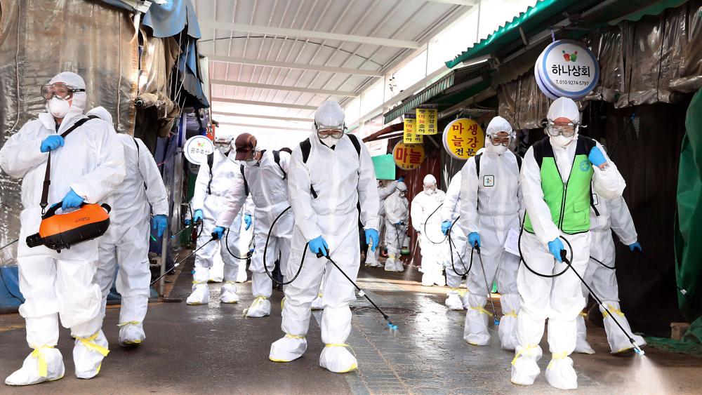Workers wearing protective suits spray disinfectant as a precaution against the coronavirus at a market in Bupyeong, South Korea, Feb. 24, 2020. South Korea reported another large jump in new virus cases. (Lee Jong-chul/Newsis via AP)