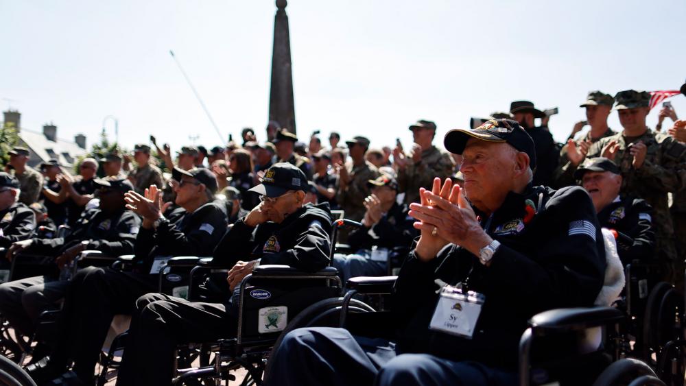 US WW II veteran Sy Tipper, right, applauds during a veterans parade in Sainte-Mere-Eglise, Normandy, Wednesday, June 5, 2024. (AP Photo/Jeremias Gonzalez)