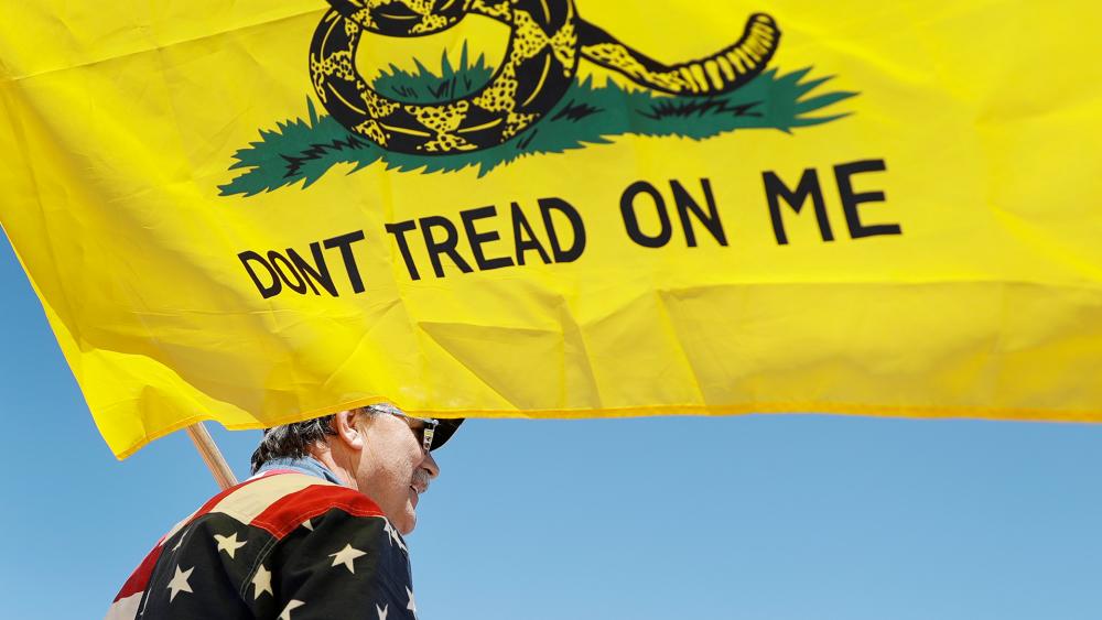 A man holds a flag as he attends a rally to protest stay-at-home orders put into place due to the COVID-19 outbreak Tuesday, April 21, 2020, outside the Missouri Capitol in Jefferson City, Mo. (AP Photo/Jeff Roberson)