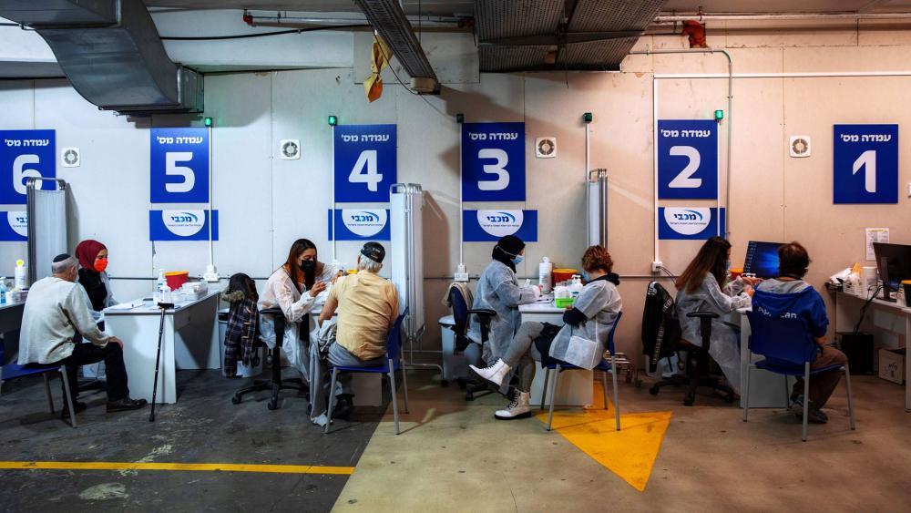 Israelis receive a Pfizer-BioNTech COVID-19 vaccine from medical professionals at a vaccination center set up on a mall parking lot in Givataim, Israel.  (AP Photo/Oded Balilty)