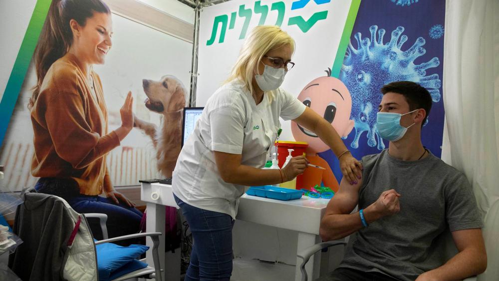 An Israeli youth receives a Pfizer-BioNTech COVID-19 vaccine in the Israeli city of Holon near Tel Aviv, Monday, Feb. 15, 2021. (AP Photo/Sebastian Scheiner)