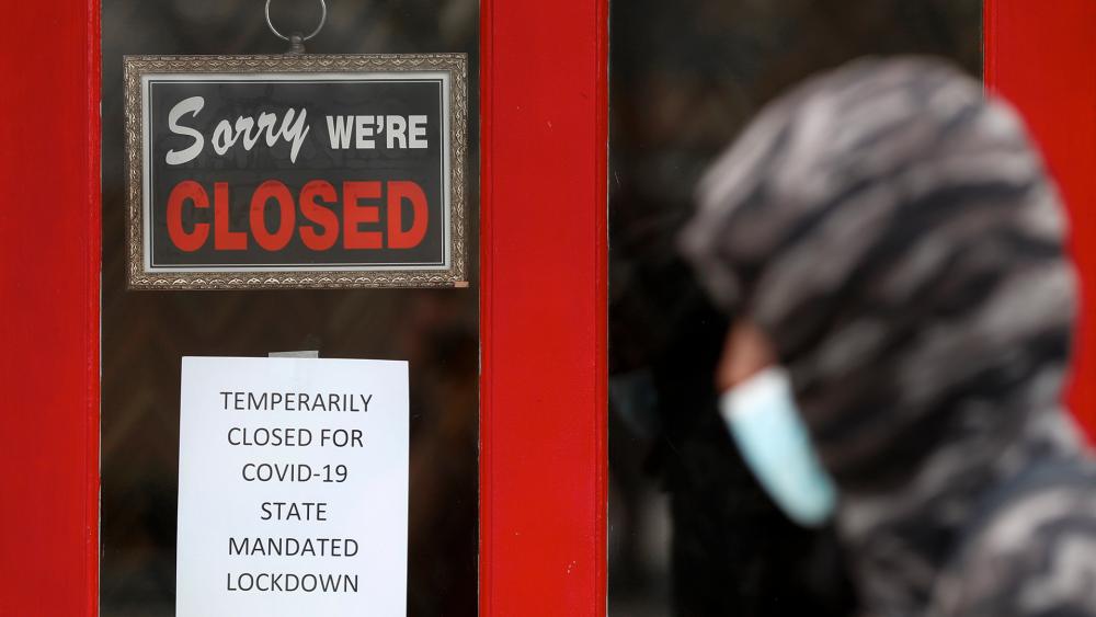 A pedestrian walks by The Framing Gallery, closed due to the COVID-19 pandemic, in Grosse Pointe, Mich. (AP Photo/Paul Sancya, File)