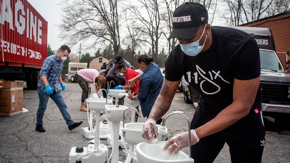 Grammy award-winning hip hop artist Lecrae assembles a portable wash station in College Park, Georgia. The wash stations were distributed by Lecrae and volunteers with Love Beyond Walls. (AP Photo/ Ron Harris)