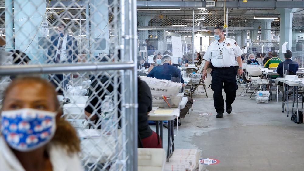 Security personnel walk through fenced workspaces at a Board of Elections facility, Wednesday, July 22, 2020, in New York. (AP Photo/John Minchillo)