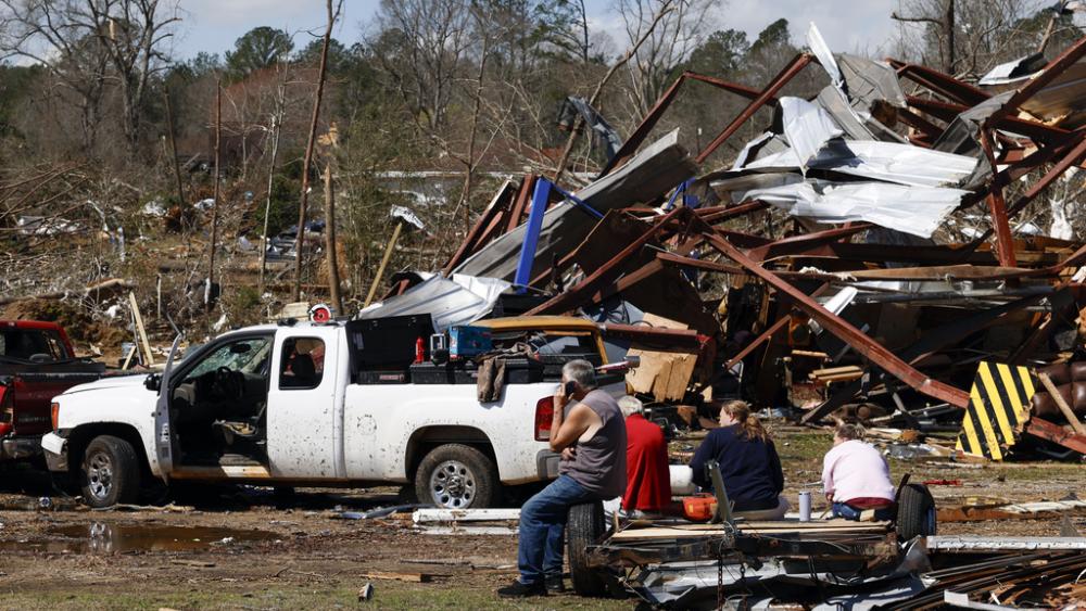 Friends and family members take a break as they search for belongings in the damage after a tornado passed through the area, Sunday, March 16, 2025, in Plantersville, Ala. (AP Photo/Butch Dill)