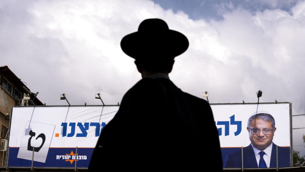 An ultra-Orthodox Jewish man walks by an election campaign billboard showing Itamar Ben-Gvir, Israeli lawmaker and the head of &quot;Jewish Power&quot; party, in Bnei Brak, Israel Monday, Oct. 24, 2022.  (AP Photo/Oded Balilty)