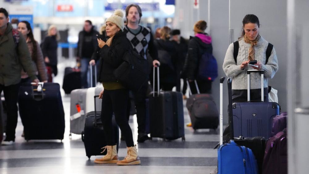 A traveler, right, checks on her cellphone as other travelers walk through Terminal 3 at O&#039;Hare International Airport in Chicago, Thursday, Dec. 22, 2022. (AP Photo/Nam Y. Huh)
