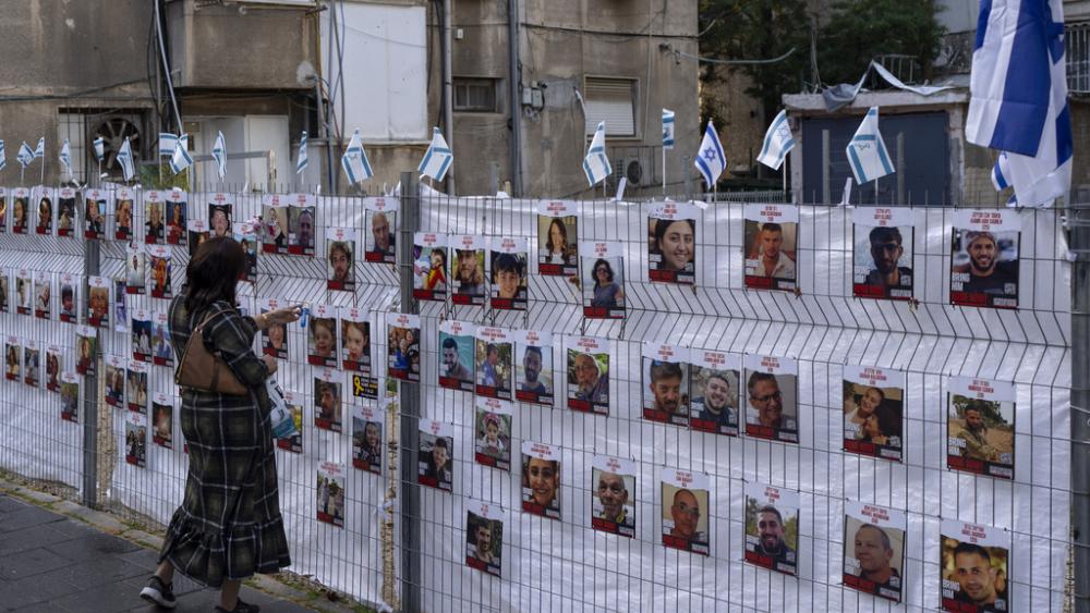 A woman looks at photographs of hostages, mostly Israeli civilians who were abducted during the Oct. 7, unprecedented Hamas attack on Israel, in Ramat Gan, Israel, Wednesday, Nov. 22, 2023. (AP Photo/Oded Balilty)