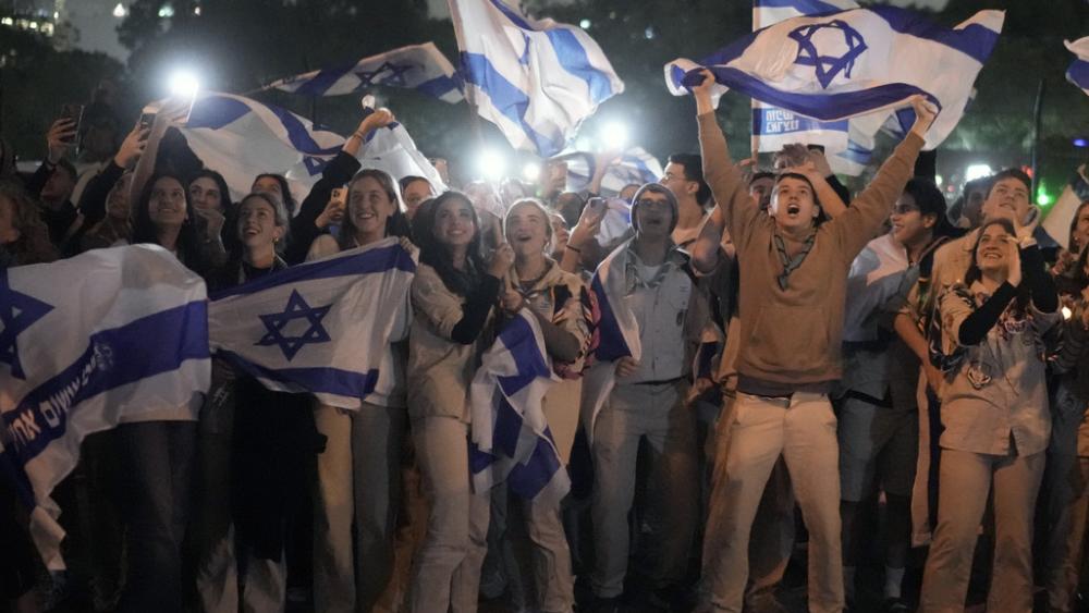 A group of Israelis celebrate as a helicopter carrying hostages released from the Gaza Strip lands at the helipad of the Schneider Children&#039;s Medical Center in Petah Tikva, Israel, Sunday Nov. 26, 2023. (AP Photo/Leo Correa)