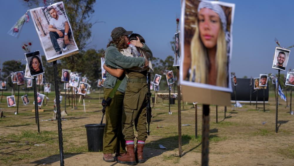 Israeli soldiers embrace next to photos of people killed and taken captive by Hamas militants during their violent rampage through the Nova music festival in southern Israel near kibbutz Re&#039;im, Friday, Dec. 1, 2023. (AP Photo/Ariel Schalit)