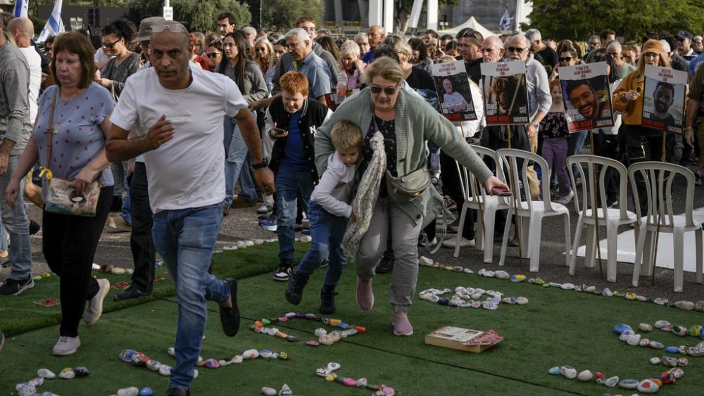 Israelis rush to a shelter as a siren sounds a warning of incoming rockets fired from the Gaza strip, in Tel Aviv, Israel, on Friday, Dec. 8, 2023. (AP Photo/Leo Correa)