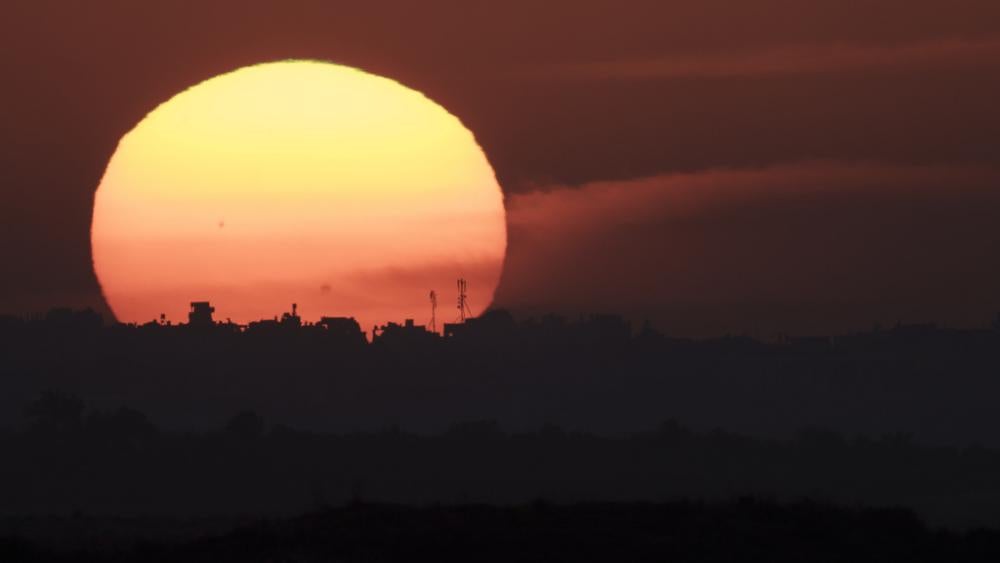 The sun sets behind the buildings in the Gaza Strip as seen from southern Israel, Tuesday, Jan. 16, 2024. (AP Photo/Leo Correa)