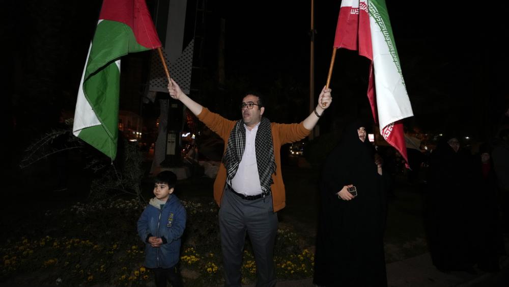 A demonstrator waves Iranian and Palestinian flags during an anti-Israeli gathering at the Felestin (Palestine) Square in Tehran, Iran, early Sunday, April 14, 2024. (AP Photo/Vahid Salemi)