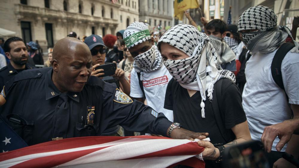 A Pro-Palestinian protester tries to grab an American flag from Pro-Israel supporters as a police officer tries to stop it during a demonstration in New York, Monday, April 15, 2024. (AP Photo/Andres Kudacki)