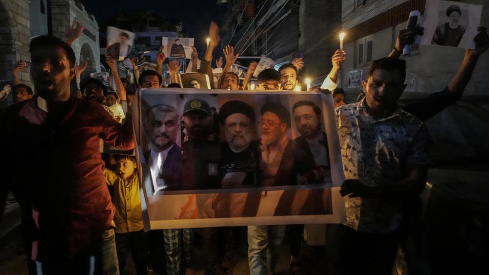Shiite Muslims hold photos of Iranian President Ebrahim Raisi and other leaders shout slogans during a candlelight vigil in Srinagar, Indian controlled Kashmir, Monday, May 20, 2024. (AP Photo/Mukhtar Khan)