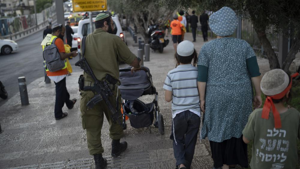 An Israeli soldier pushes a baby stroller as he carries his weapon outside Jerusalem&#039;s Old City walls, Sunday, Aug. 11, 2024. (AP Photo/Leo Correa)