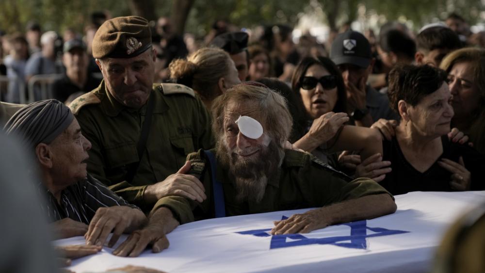 People mourn over the flagged-covered coffin of Israeli soldier Sgt. Amitai Alon, killed by a Hezbollah drone attack, during his funeral near Ramot Naftali, Israel, Monday, Oct. 14, 2024. (AP Photo/Leo Correa)