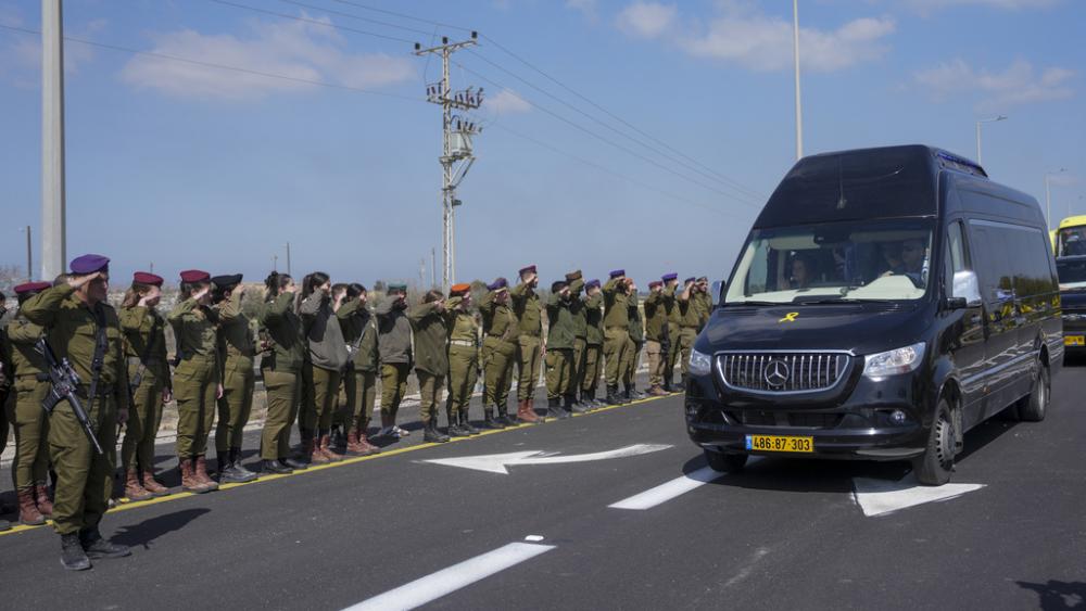 Israeli soldiers salute as the convoy carrying the coffins of slain hostages Shiri Bibas and her two children, Ariel and Kfir, pass by near Kibbutz Nir Oz, southern Israel, Wednesday, Feb. 26, 2025. (AP Photo/Ohad Zwigenberg)