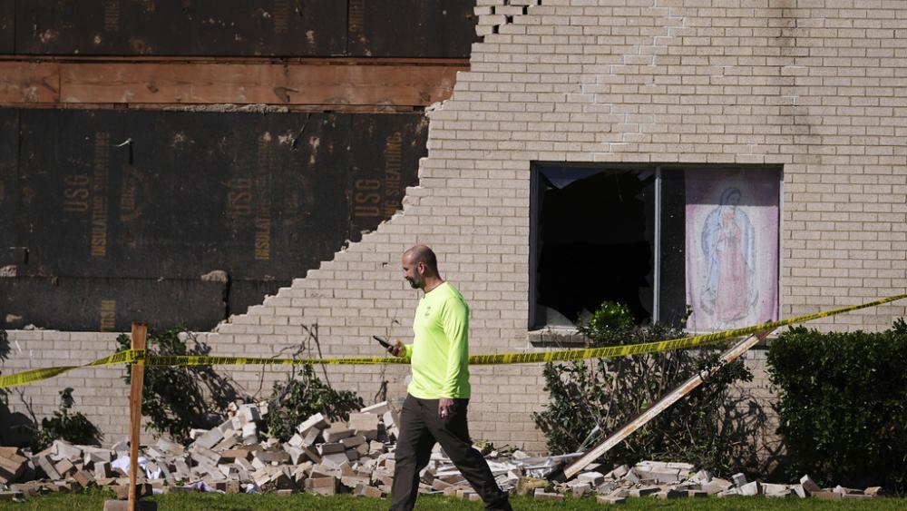 A person walks near a building damaged by an early morning storm that hit the Dallas region Tuesday, March 4, 2025, in Irving, Texas. (AP Photo/Julio Cortez)