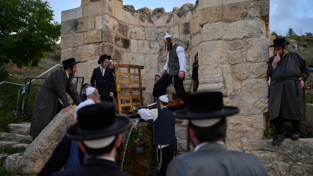 Ultra-Orthodox Jewish men gather to collect water from a spring to make matzoh, a traditional handmade unleavened bread for the holiday of Passover, at a mountain spring outside Jerusalem, April 10, 2025. (AP Photo/Ohad Zwigenberg)