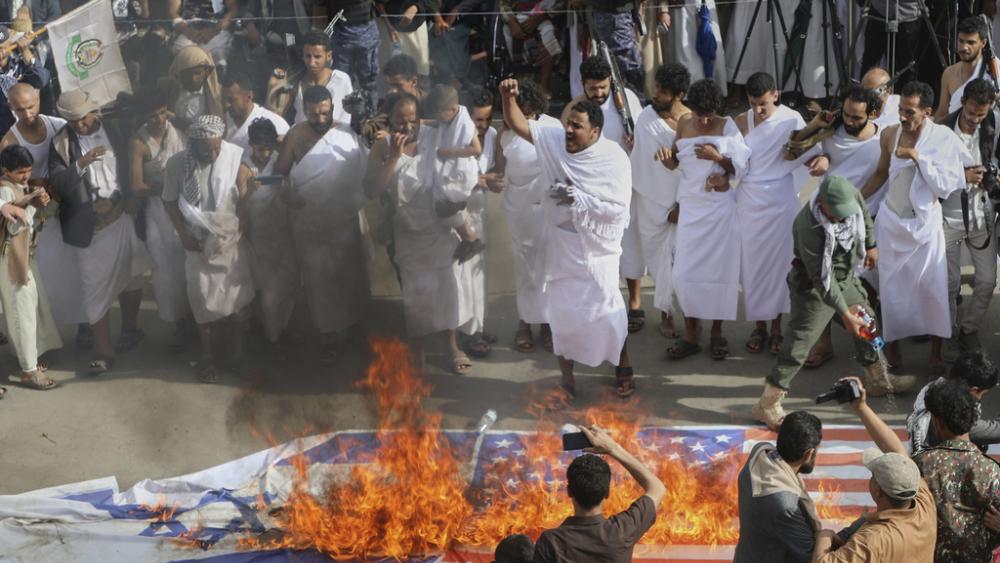 Houthi supporters in Muslim pilgrim dress burn American and Israeli flags during an anti-U.S. and anti-Israel rally in Sanaa, Yemen, May 30, 2025. (AP Photo/Osamah Abdulrahman)