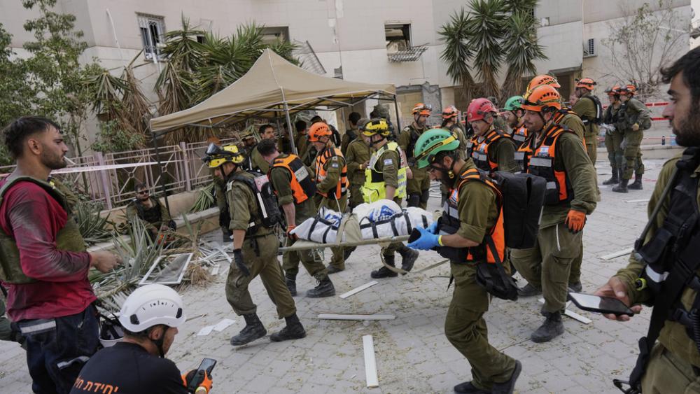 Israeli soldiers and rescue workers carry a body from a residential building destroyed by an Iranian missile strike that killed several people, in Beersheba, Israel, on Tuesday, June 24, 2025. (AP Photo/Bernat Armangue)
