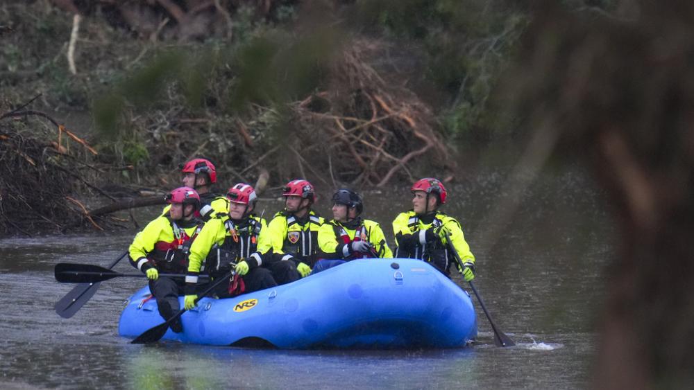 Officials ride a boat as they arrive to assist with a recovery effort at Camp Mystic along the Guadalupe River after a flash flood swept through the area Sunday, July 6, 2025, in Hunt, Texas. (AP Photo/Julio Cortez)