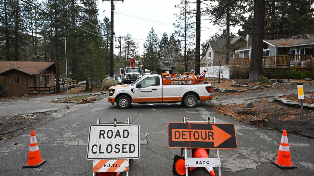 Workers work to restore power after severe storms, Thursday, Dec. 25, 2025, in Wrightwood, Calif. (AP Photo/William Liang)