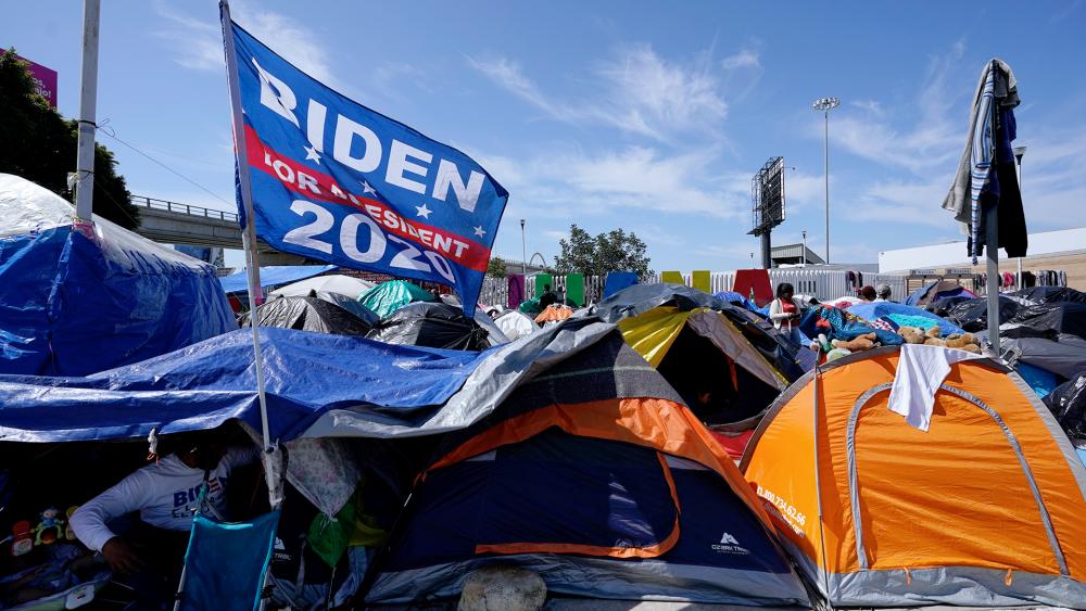 A campaign flag for President Joe Biden flies over tents at a camp of migrants at the border port of entry leading to the U.S., March 17, 2021, in Tijuana, Mexico. (AP Photo/Gregory Bull)