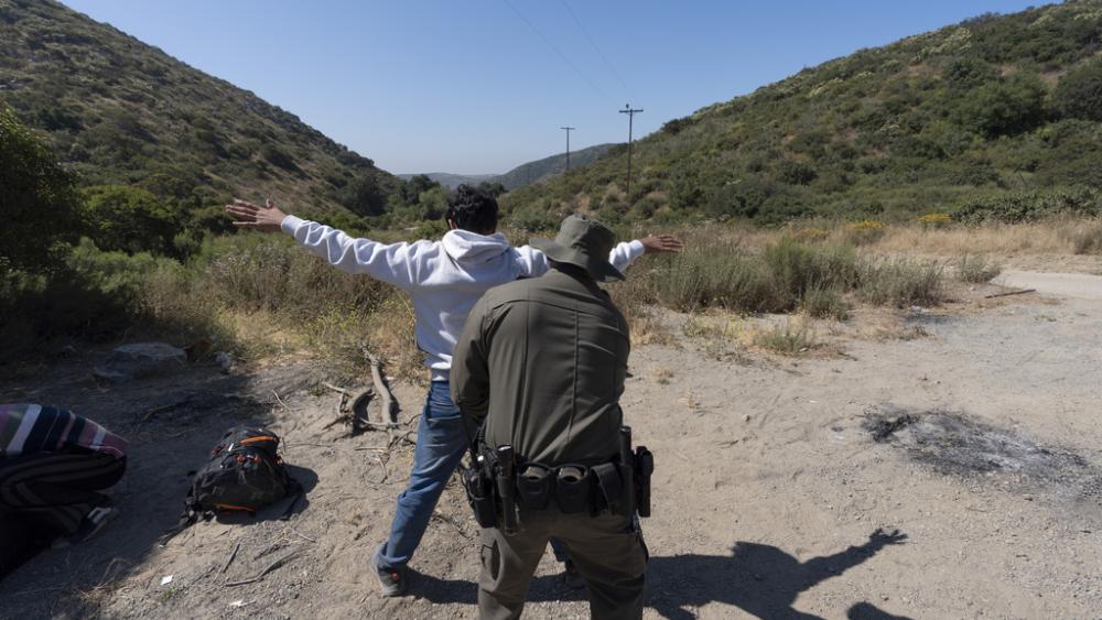 A Border Patrol agent apprehends a migrant near Dulzura, CA (AP Photo/Gregory Bull)