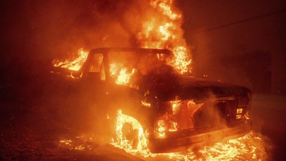 The Eaton Fire burns a vehicle Wednesday, Jan. 8, 2025 in Altadena, Calif. (AP Photo/Ethan Swope)