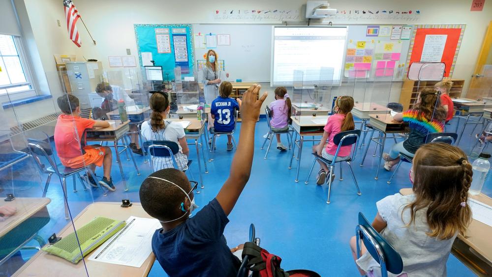 A teacher and her third grade students wear face masks and are seated with social distancing spacing (AP Photo/Mary Altaffer, File)