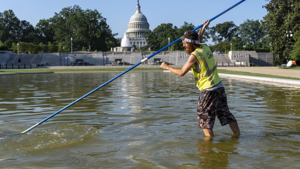 Working before the temperature hits 100 degrees today, Jeffrey Adcock cleans the reflecting pool in Lower Senate Park at the Capitol in Washington, Tuesday, June 24, 2025. (AP Photo/J. Scott Applewhite)